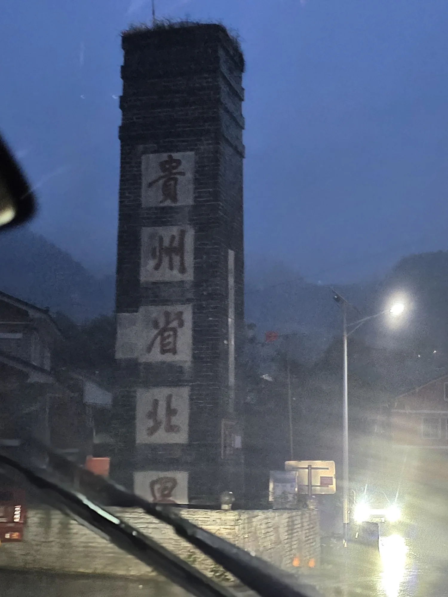 贵州省北界，雨夜，隔着挡风玻璃。界碑背面写着“大中華民國三十五年二月”。